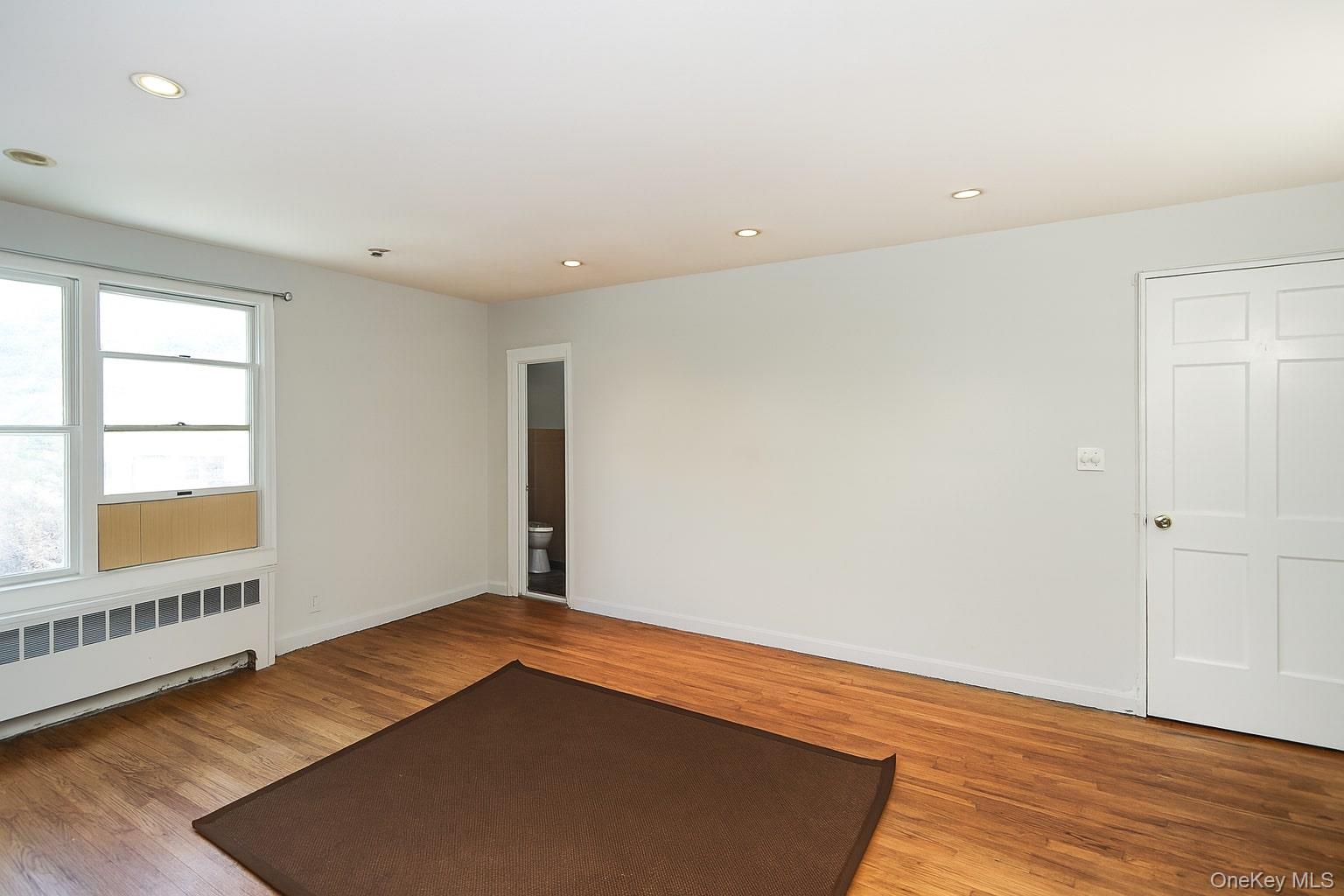 10 Glen Keith Road, Unit U Glen Cove, NY 11542 - Photo 9 of 22 an empty room with wooden floor and windows