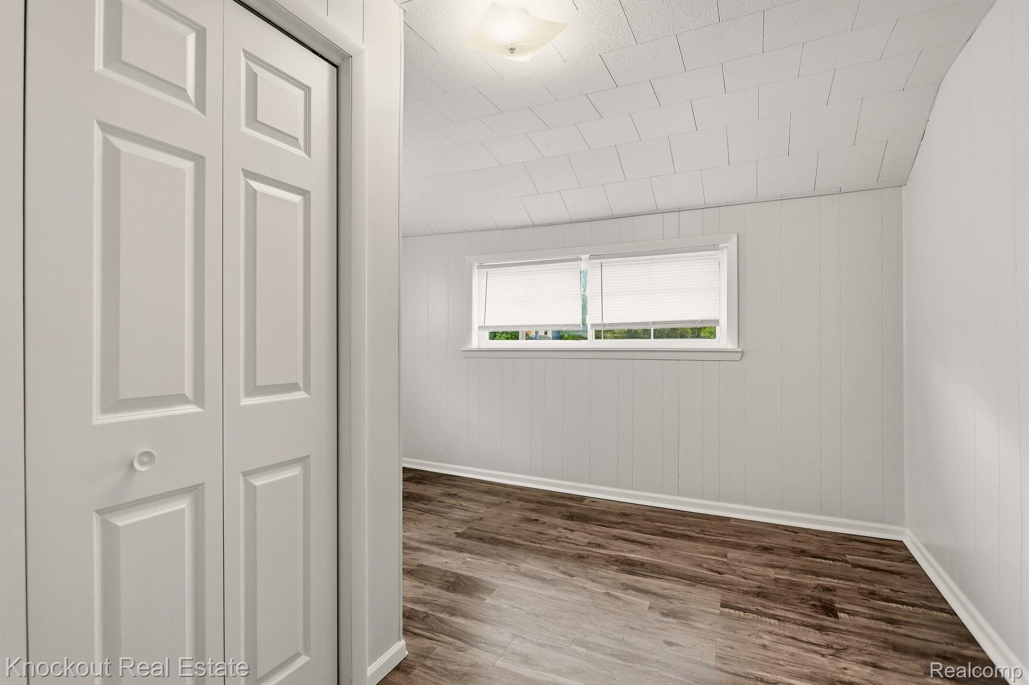 8771 Van Cleve Road Vassar, MI 48768 - Photo 23 of 44 Wood-finish flooring, white paneled walls, and a window with blinds