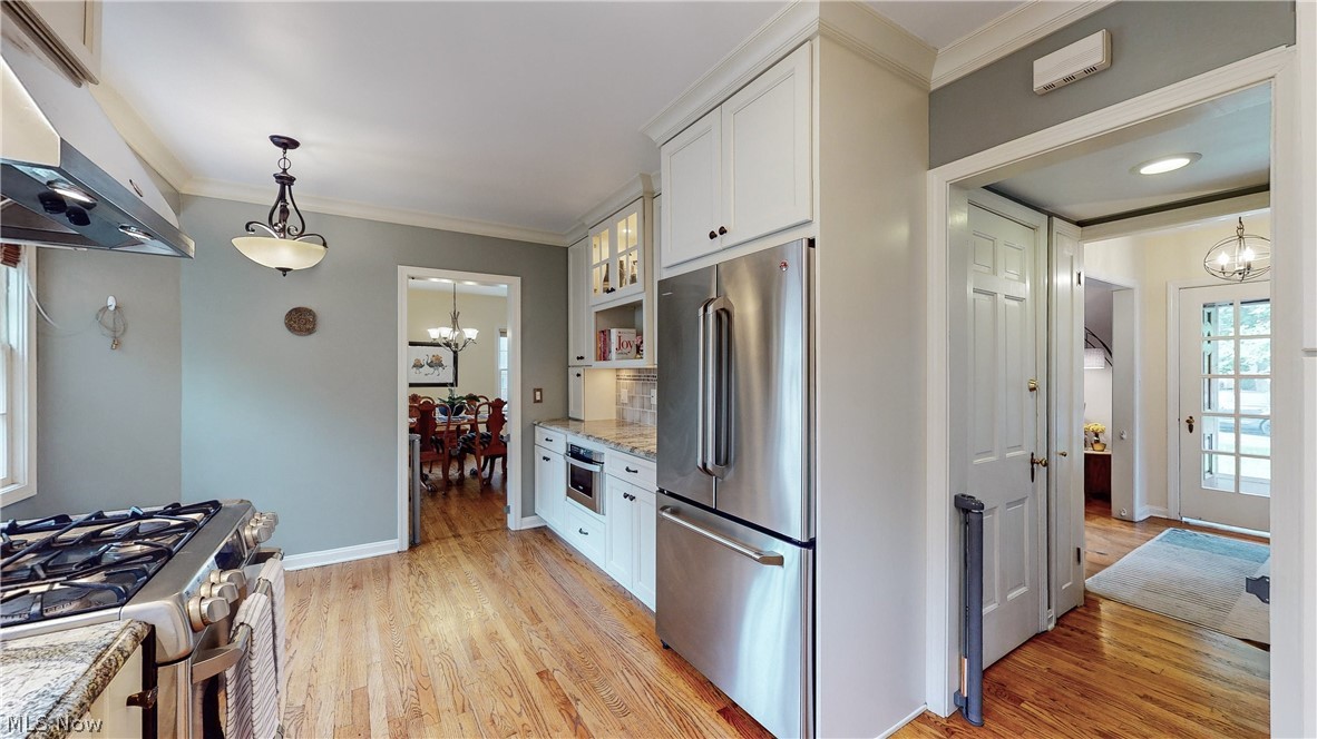 3658 Traver Road Shaker Heights, OH 44122 - Photo 11 of 33 Kitchen featuring light wood-type flooring, pendant lighting, light stone counters, white cabinets, and appliances with stainless steel finishes