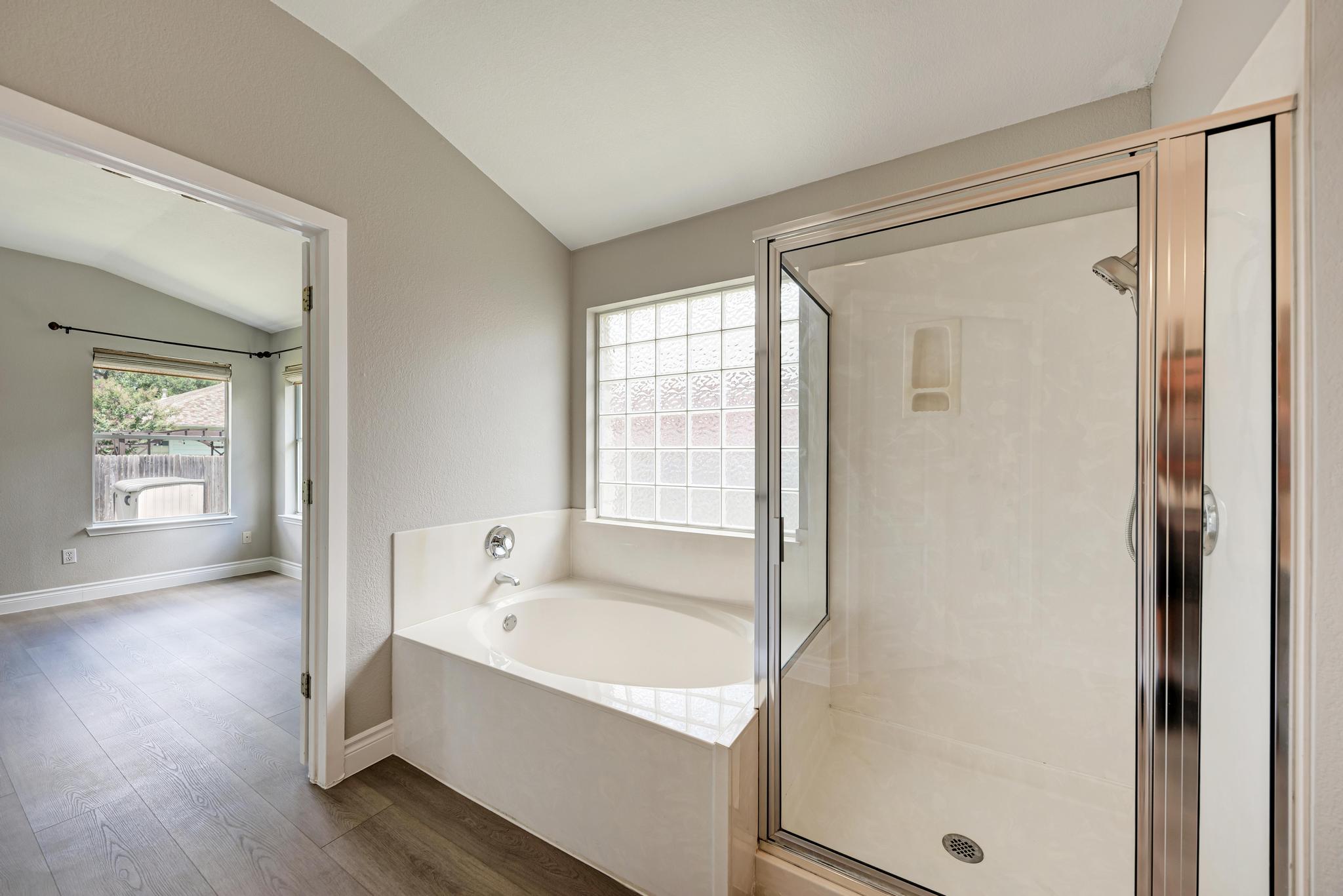 4408 Tello Path Austin, TX 78749 - Photo 23 of 38 Bathroom featuring lofted ceiling, a garden tub, wood finished floors, and a shower stall