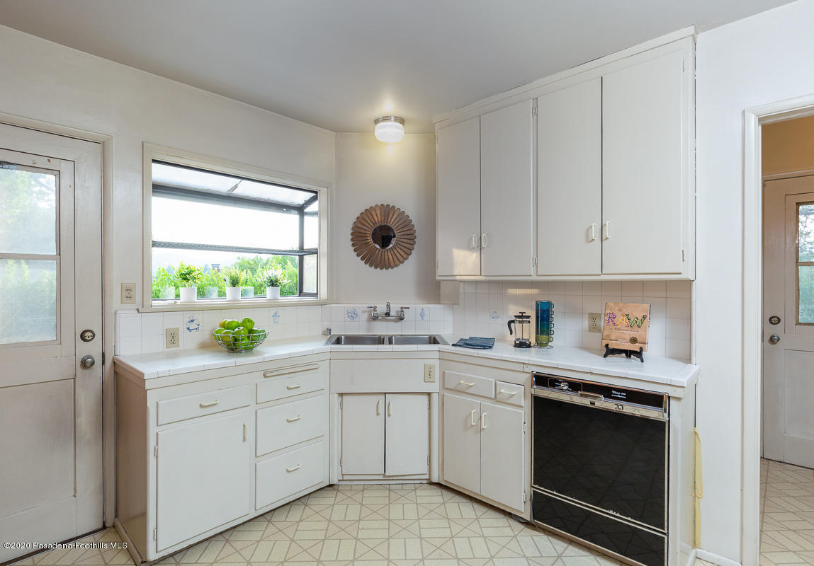 1839 North Arroyo Boulevard Pasadena, CA 91103 - Photo 9 of 36 a kitchen with a sink dishwasher and white cabinets with wooden floor