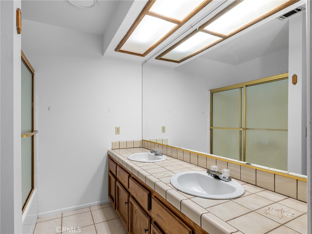 13901 Hidden Valley Road Victorville, CA 92395 - Photo 25 of 31 a bathroom with a granite countertop sink and a mirror