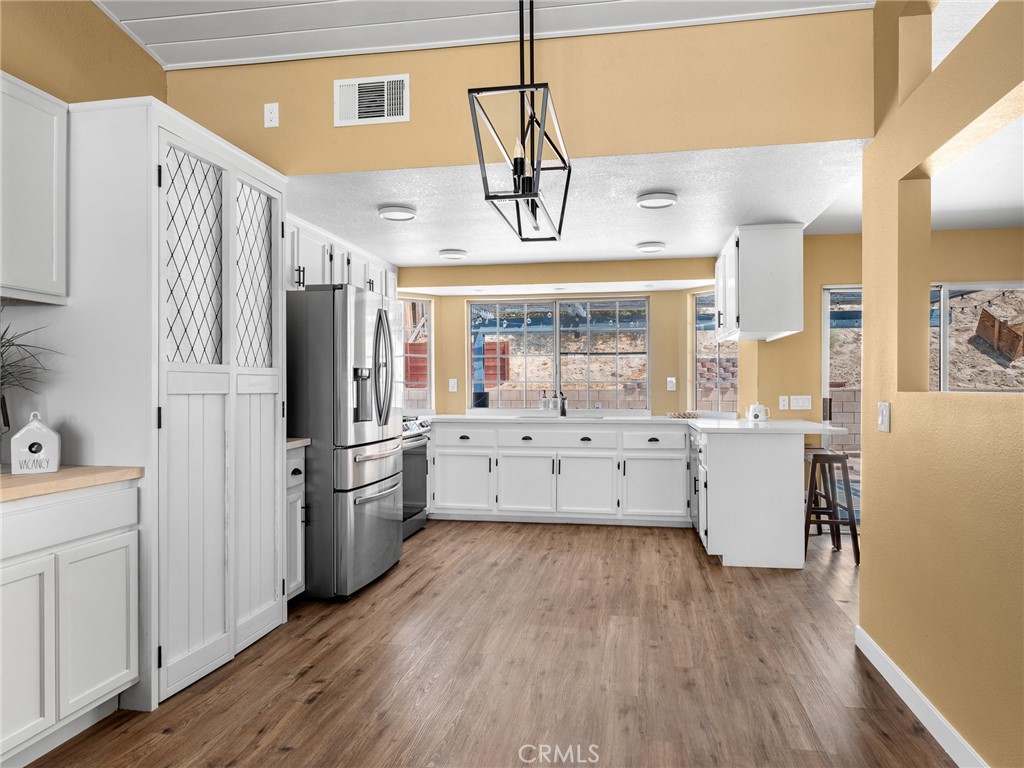 13901 Hidden Valley Road Victorville, CA 92395 - Photo 9 of 31 a kitchen with stainless steel appliances a refrigerator a sink dishwasher and white cabinets with wooden floor