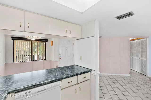 a view of an empty room with a window and a kitchen