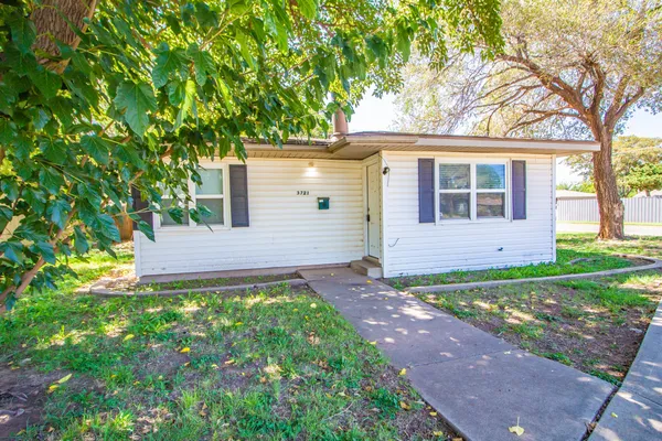 a view of a house with a small yard plants and large tree