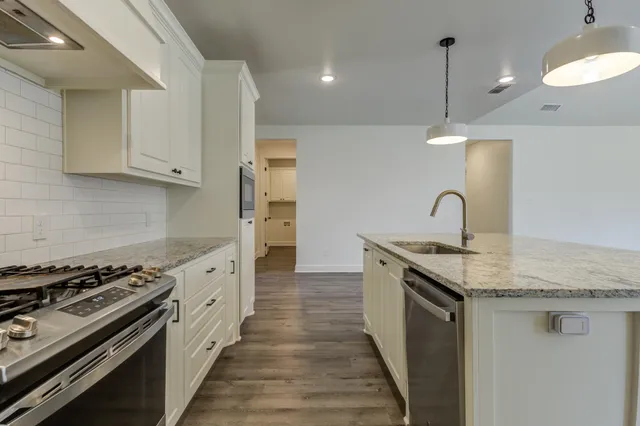 a kitchen with granite countertop a sink stove and cabinets