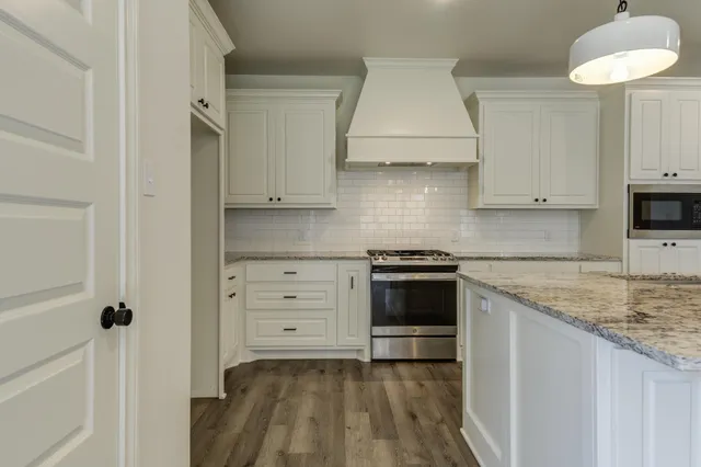 a kitchen with granite countertop white cabinets and appliances