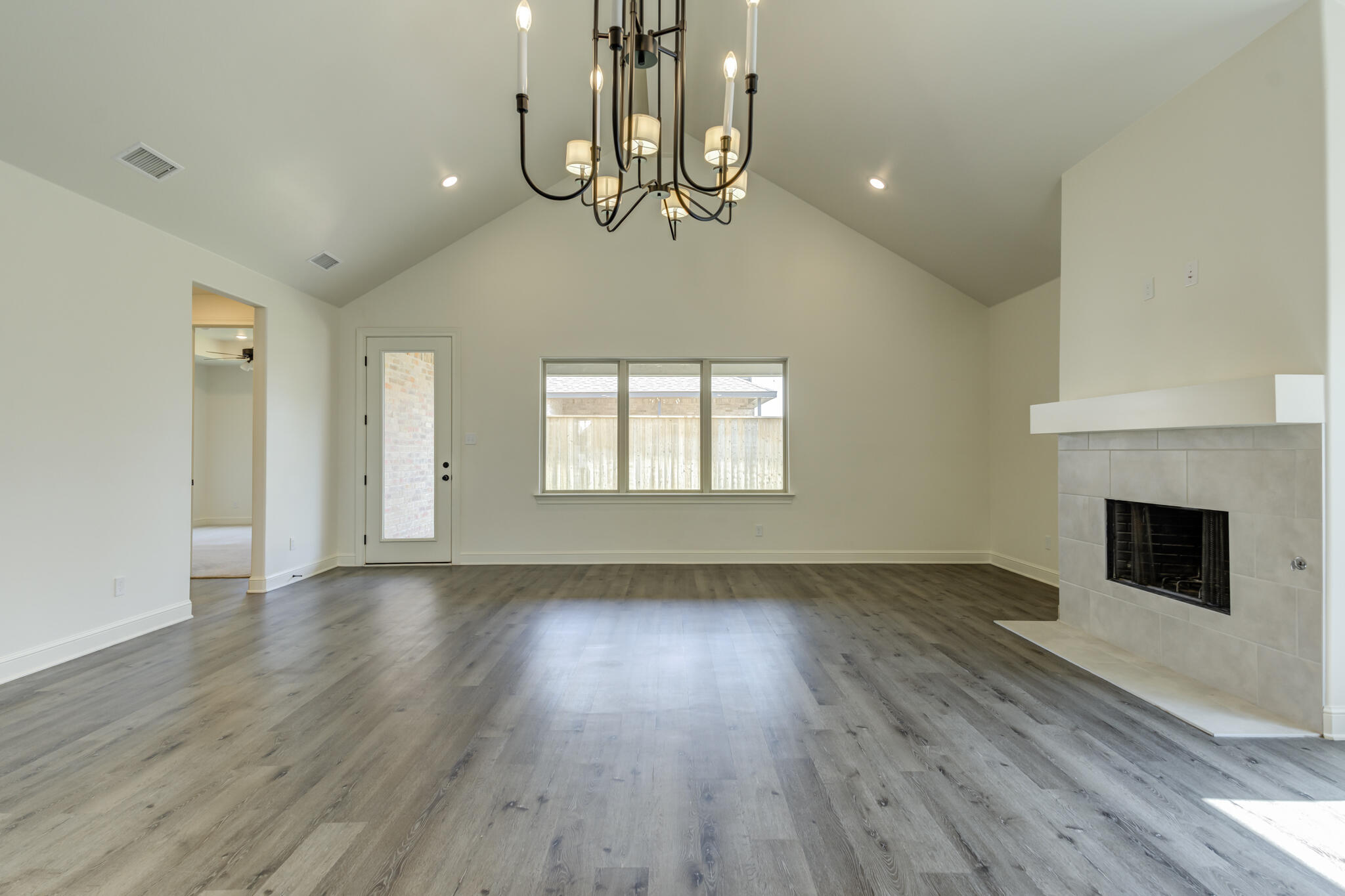 6904 55th Street Lubbock, TX 79407 - Photo 15 of 47 a view of an empty room with wooden floor fireplace and a window