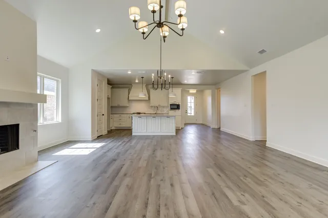 a view of a hallway with wooden floor a kitchen a chandelier and entryway