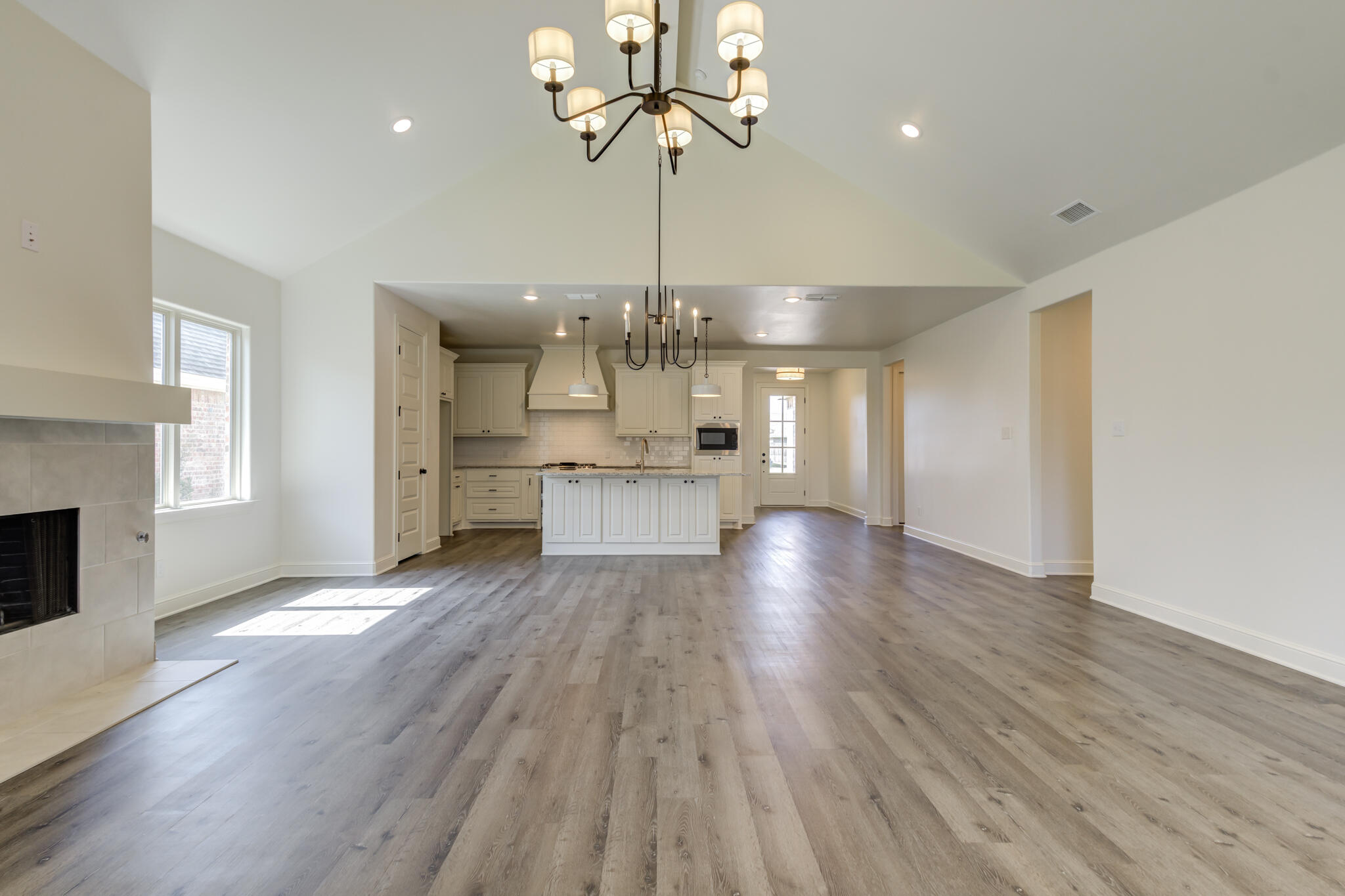 6904 55th Street Lubbock, TX 79407 - Photo 20 of 47 a view of a hallway with wooden floor a kitchen a chandelier and entryway