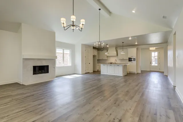 a view of a big room with wooden floor and kitchen