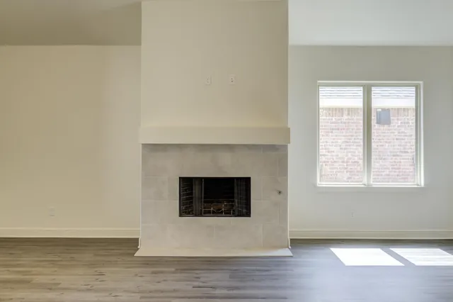 a view of an empty room with wooden floor and a fireplace