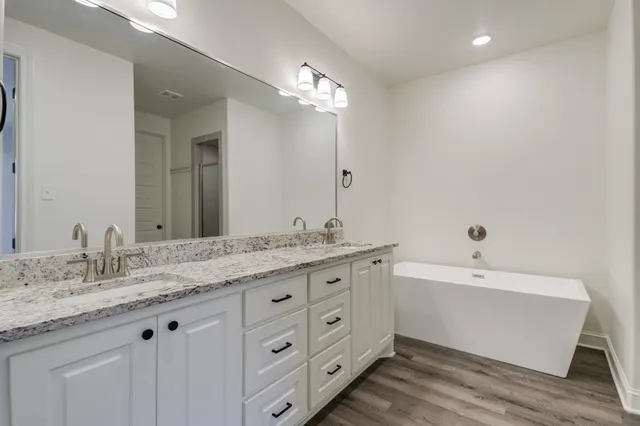 a spacious bathroom with a granite countertop sink a mirror and shower