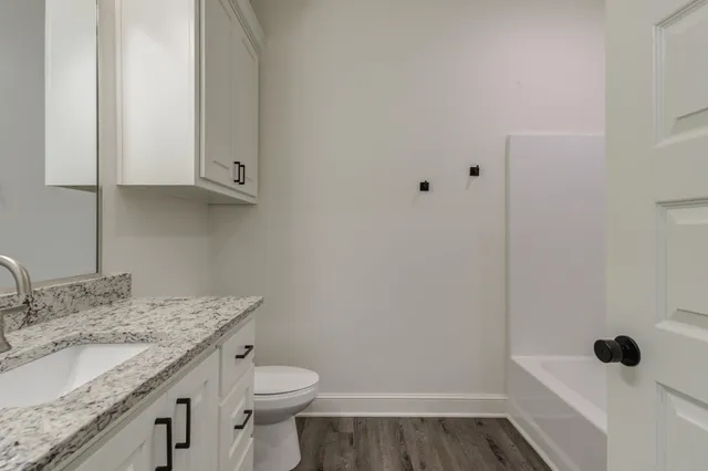 a bathroom with a granite countertop sink a toilet and mirror