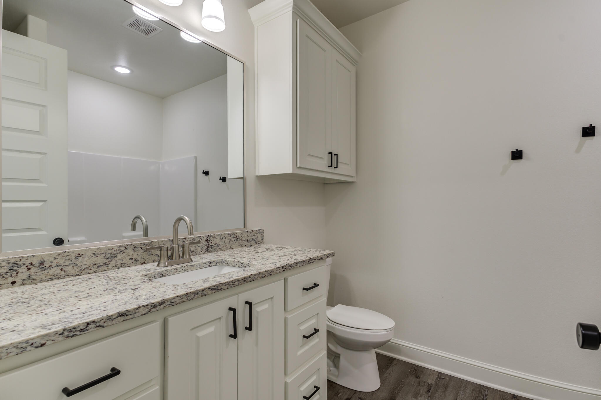 6904 55th Street Lubbock, TX 79407 - Photo 39 of 47 a bathroom with a granite countertop sink a toilet and mirror