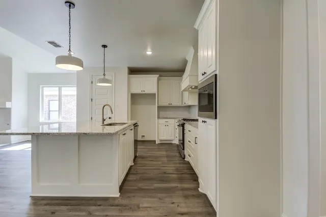 a kitchen with stainless steel appliances granite countertop a sink a stove and a wooden floors