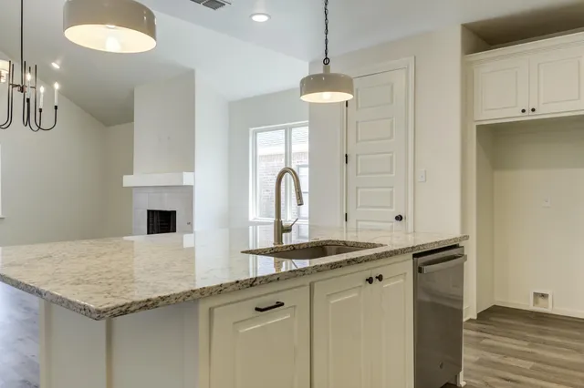 a kitchen with stainless steel appliances granite countertop a white cabinets and a wooden floor