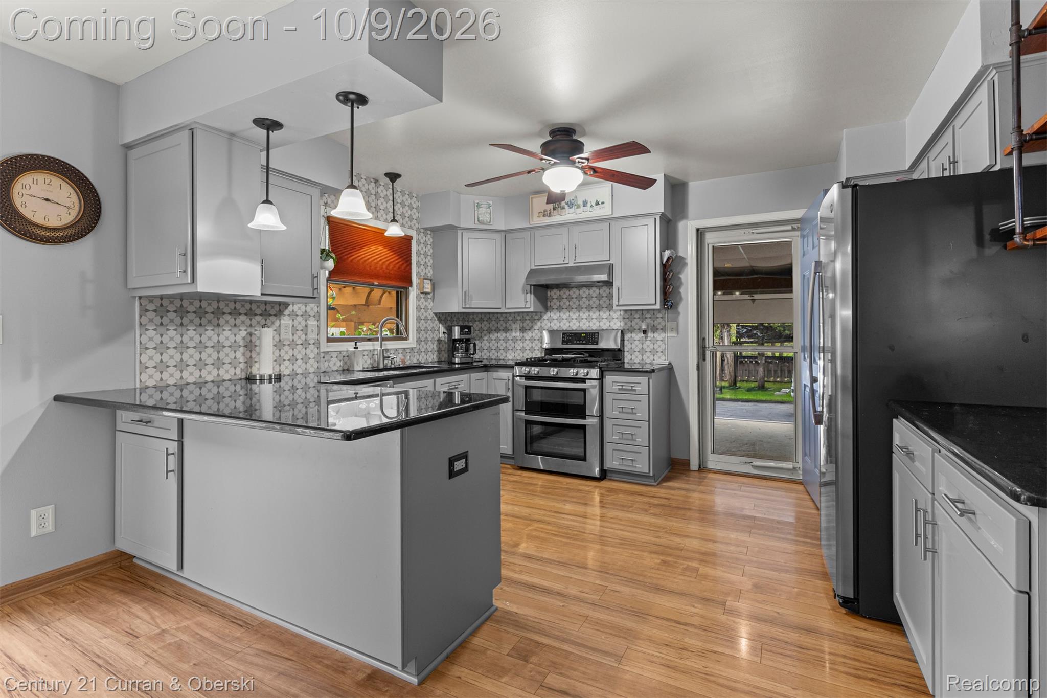 43040 Willis Road Belleville, MI 48111 - Photo 15 of 65 Kitchen featuring an integrated breakfast bar, light wood-finish flooring, stainless steel appliances, pendant lighting, and patterned tile backsplash