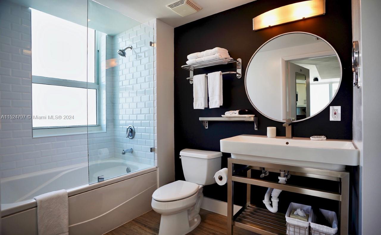 2889 McFarlane Road, Unit 2017 Coconut Grove, FL 33133 - Photo 15 of 19 a bathroom with a toilet a sink and a mirror