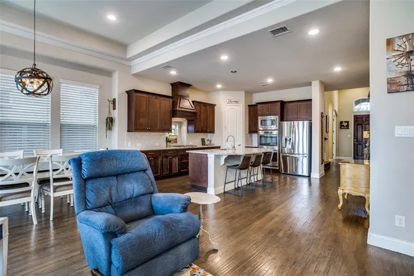 a living room with furniture kitchen view and a wooden floor