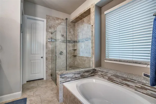 a bathroom with a granite countertop bathtub and a shower