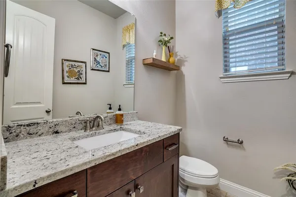 a bathroom with a granite countertop sink a toilet and a mirror