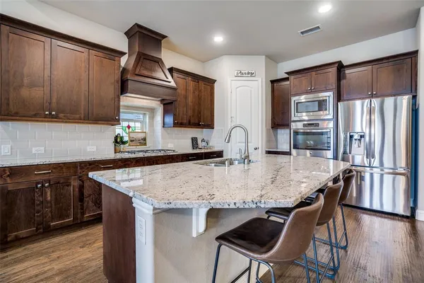 a kitchen with stainless steel appliances granite countertop a sink a stove a refrigerator and cabinets