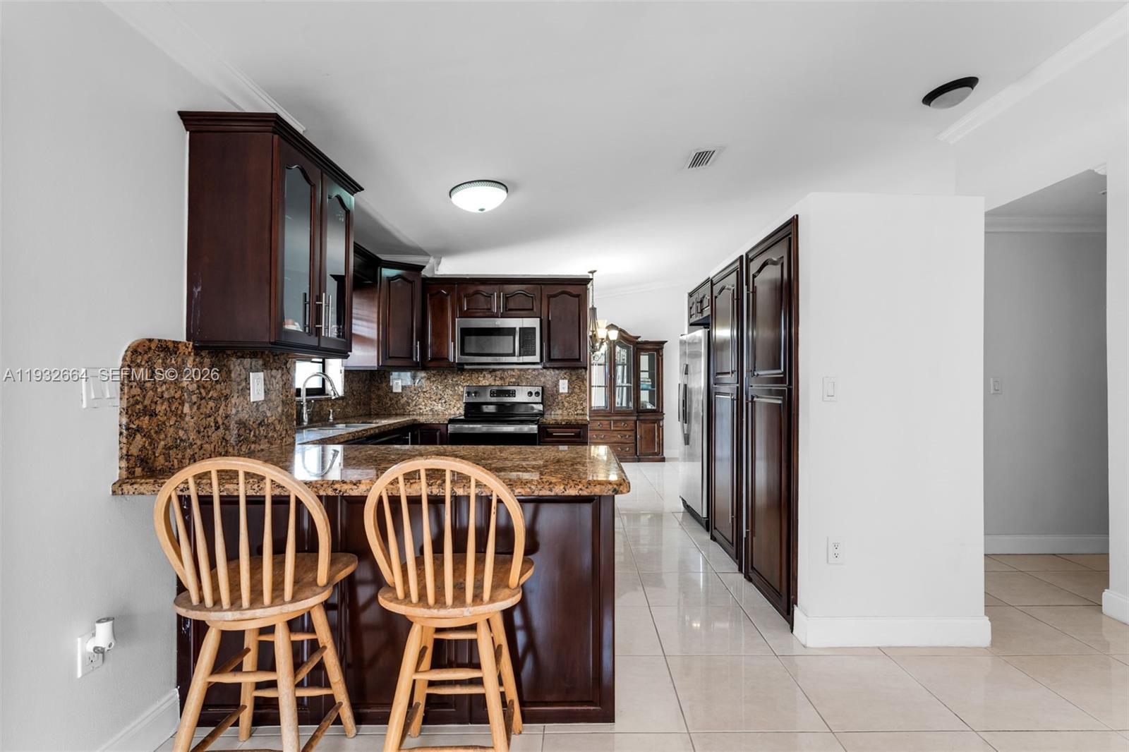 10290 Southwest 145th Place Miami, FL 33186 - Photo 15 of 50 a kitchen with stainless steel appliances granite countertop a refrigerator a stove a sink a dining table and chairs
