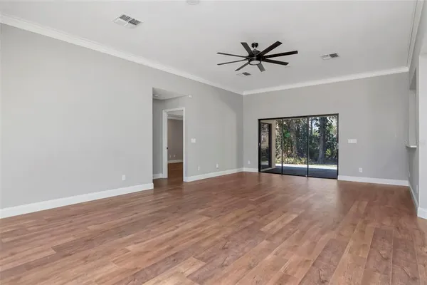 a view of an empty room with a window and wooden floor