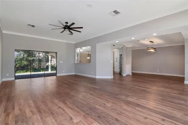 a view of an empty room with window and wooden floor