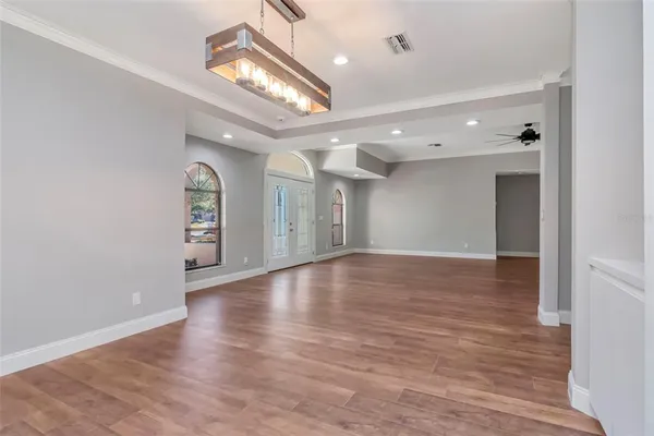 a large white kitchen with a refrigerator a sink dishwasher a stove and a dining table with wooden floor