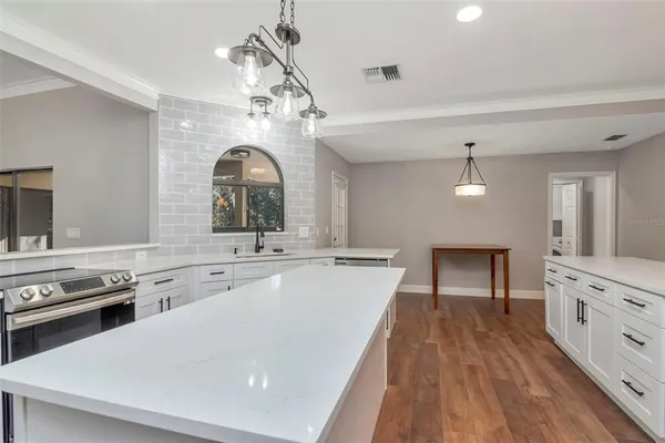 a large kitchen with a stove a sink a window and dining table