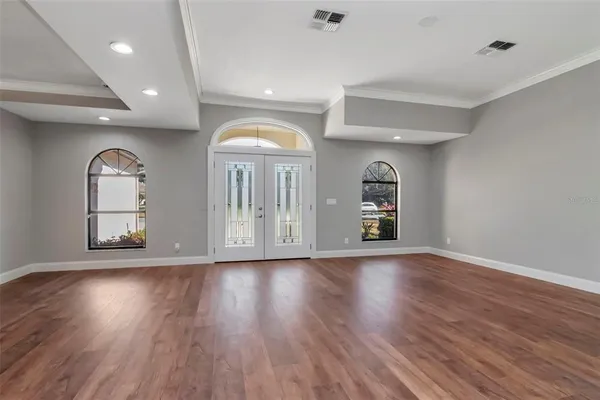 an empty room with wooden floor and windows