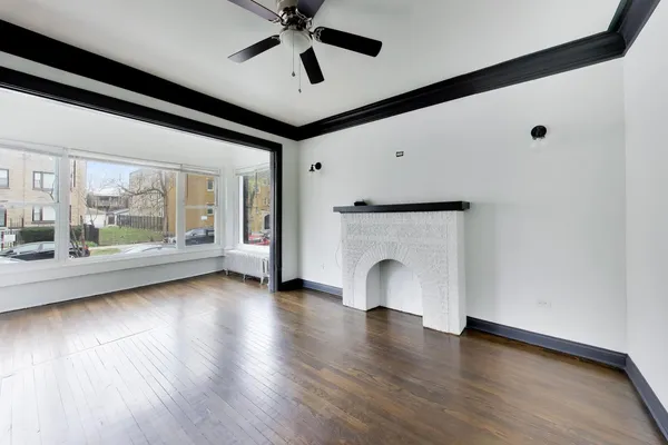 a view of an empty room with a fireplace and wooden floor