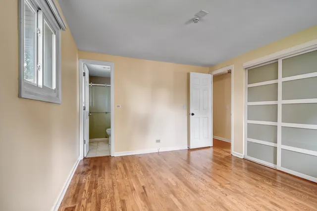 a view of an empty room with wooden floor and closet
