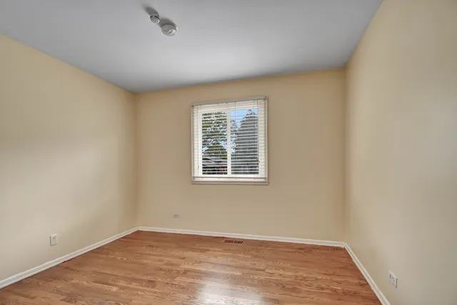an empty room with wooden floor and a window