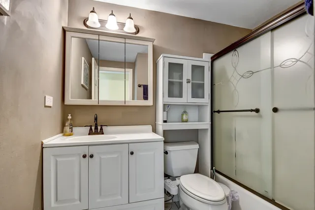 a bathroom with a sink a toilet a mirror and shower