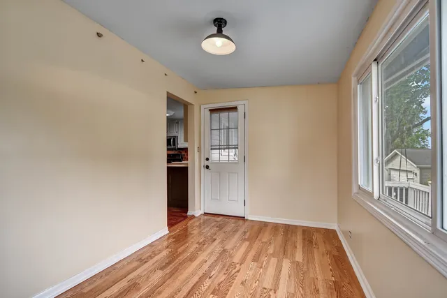 a view of an empty room with window and wooden floor