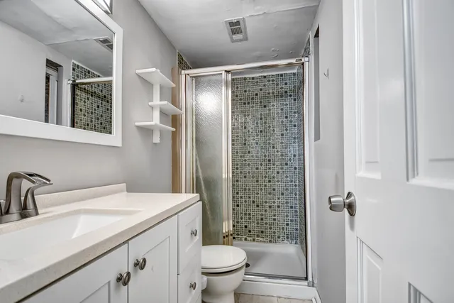 a bathroom with a shower sink vanity mirror and toilet