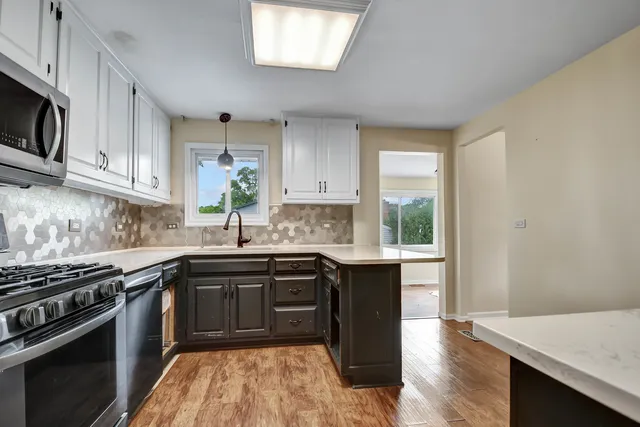 a kitchen with stainless steel appliances granite countertop a sink a stove a microwave and cabinets