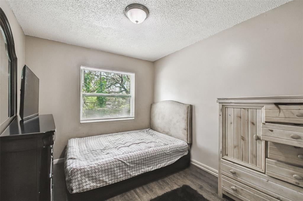 7902 North 14th Street Tampa, FL 33604 - Photo 21 of 25 a bedroom with a bed and a flat tv screen on a dresser