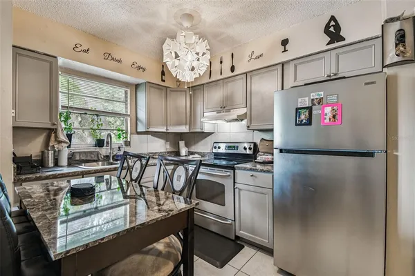 a kitchen with stainless steel appliances granite countertop a refrigerator sink stove and cabinets