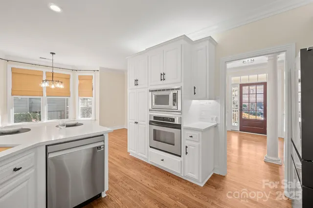 a kitchen with stainless steel appliances white cabinets and wooden floors