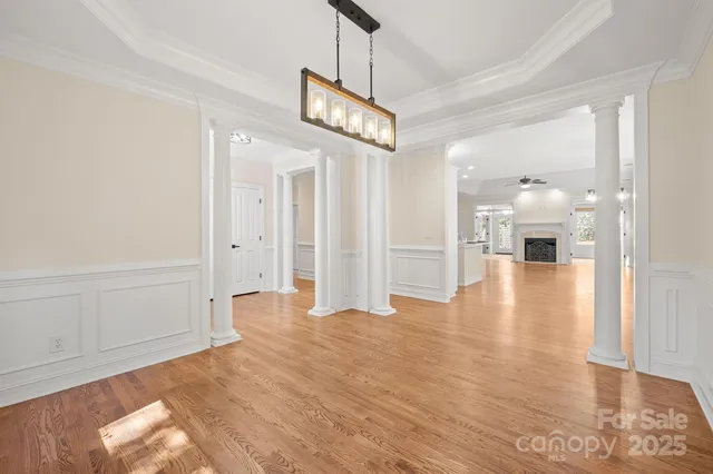 a view of a hallway with wooden floor and a chandelier