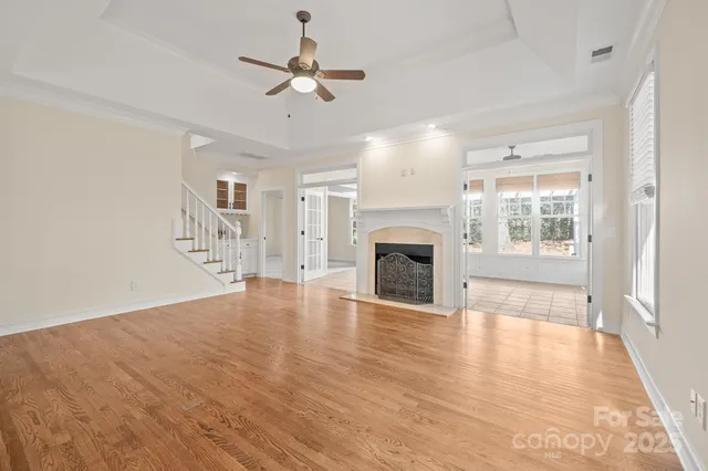 an empty room with wooden floor fireplace and windows