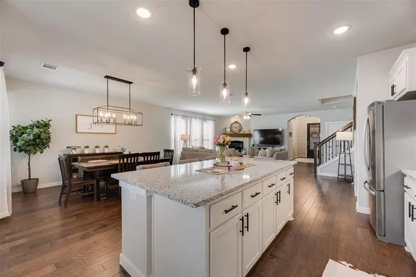 a large kitchen with kitchen island a stove a sink a center island and wooden floor