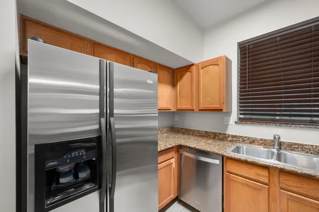 a view of kitchen with granite countertop cabinets and refrigerator