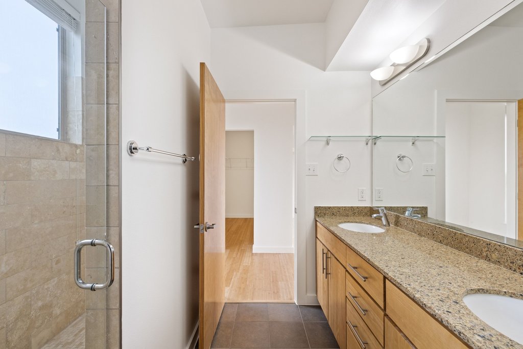 7412 Ava Lane Austin, TX 78724 - Photo 19 of 28 Bathroom with double vanity, a shower stall, and dark tile patterned flooring