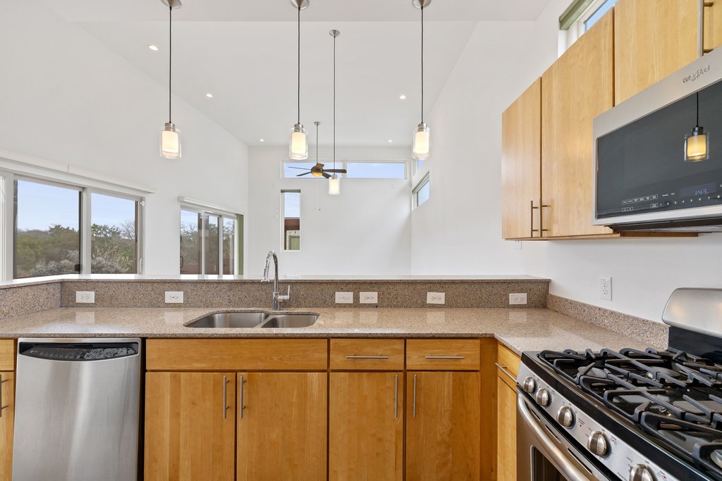 7412 Ava Lane Austin, TX 78724 - Photo 10 of 28 Kitchen featuring stainless steel appliances, hanging light fixtures, light stone counters, ceiling fan, and a high ceiling