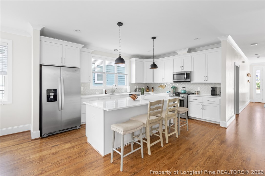 398 Carolina Avenue Raleigh, NC 27606 - Photo 14 of 50 a kitchen with stainless steel appliances a refrigerator a stove a sink dishwasher and a dining table with wooden floor